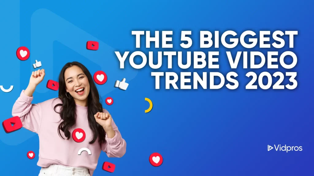 A smiling person in a pink sweater is surrounded by social media icons like hearts and thumbs up. The blue background features the text The 5 Biggest YouTube Video Trends 2023, highlighting exciting shifts in video content.