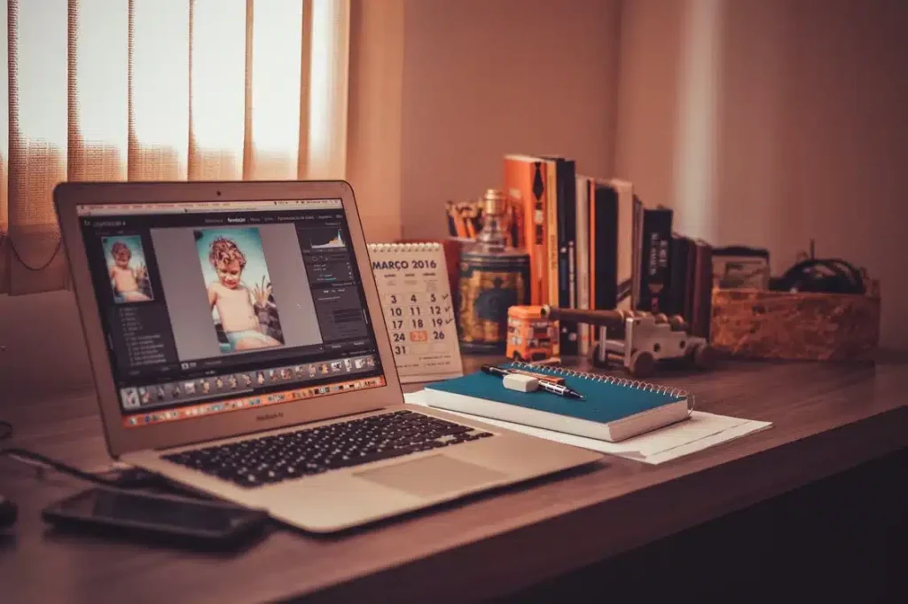 alt= "Image of a laptop computer on a desk with an image of a baby on the screen or monitor"