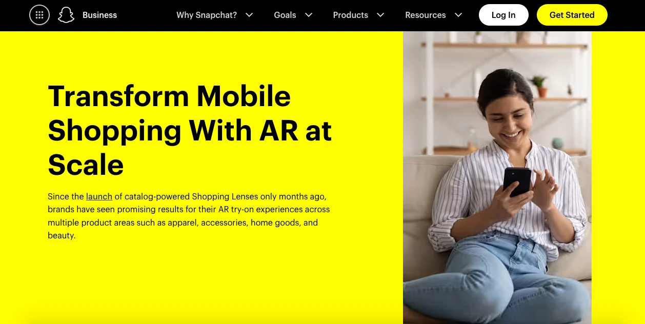 A woman sits on a couch, smiling as she looks at her phone. The background is bright yellow with text promoting augmented reality (AR) shopping. The website menu is visible at the top.