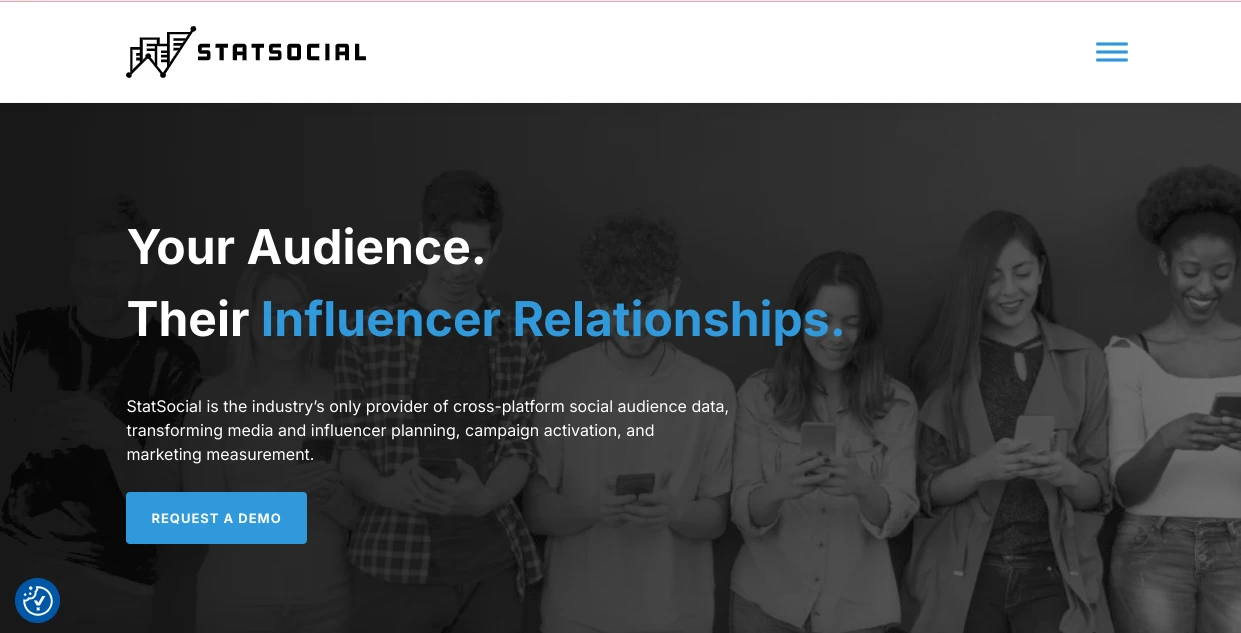 A group of diverse people looking at their phones against a dark background. Large text reads, Your Audience. Their Influencer Relationships. Includes the StatSocial logo. A button says, Request a Demo.